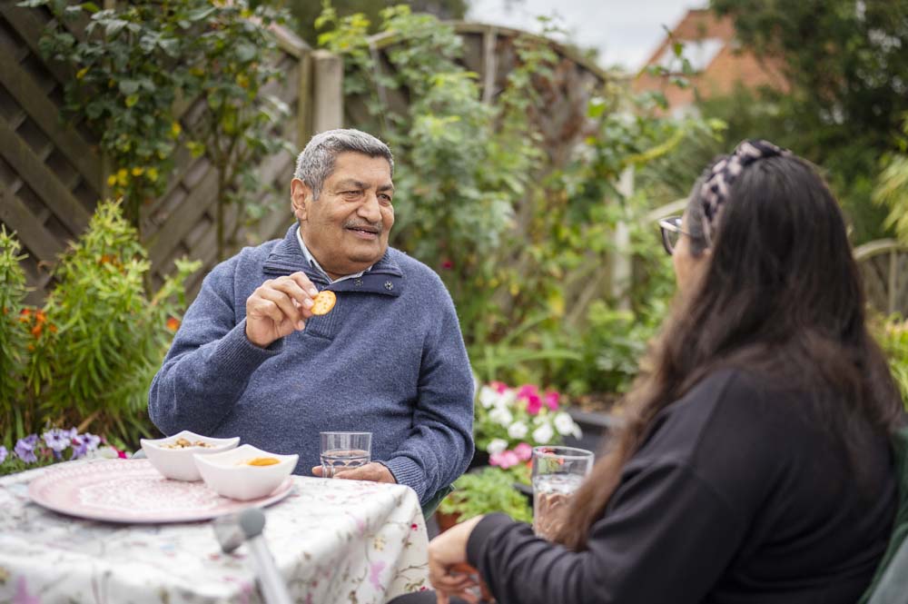 People in garden conversing over drinks and snacks.